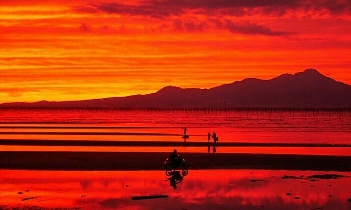 夕焼けの海岸を走るバイク
