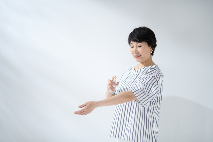 肌にスプレーを吹きかけている女性