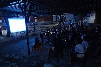 木洩れ日と清流のキャンプ場で映画を見る人たち