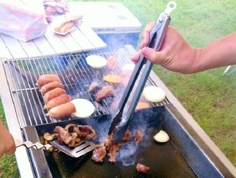 バーベキューコンロで肉を焼いている人
