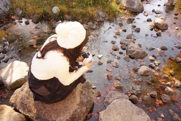 小川の写真をとる女性