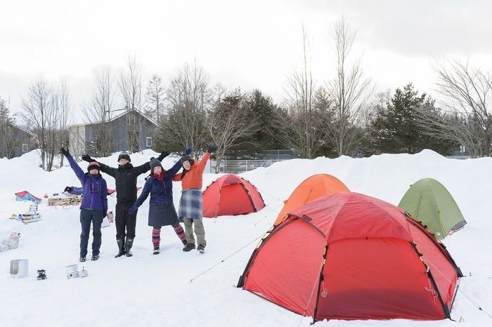 雪の上に張ったテントの前でバンザイしている4人組