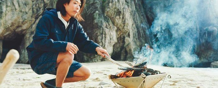 焚き火ウェアをきて焚き火をする様子
