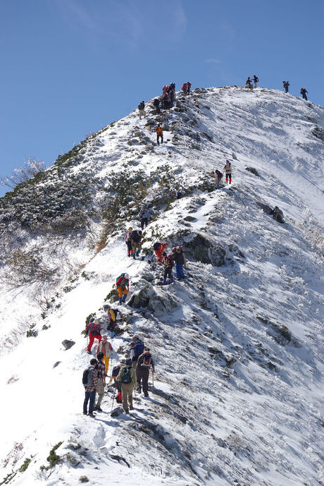 険しい雪山を登る人々