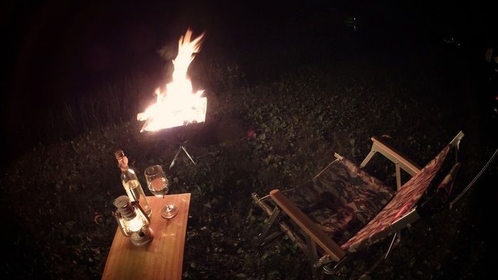 焚火を見ながらお酒を楽しむ夜のソロキャンプの様子