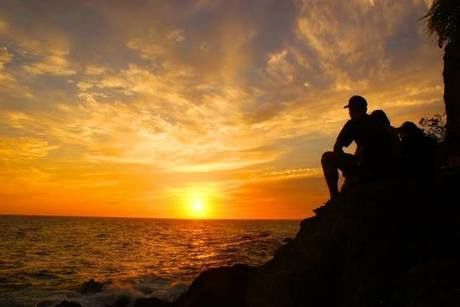 海に沈む夕日をみる人