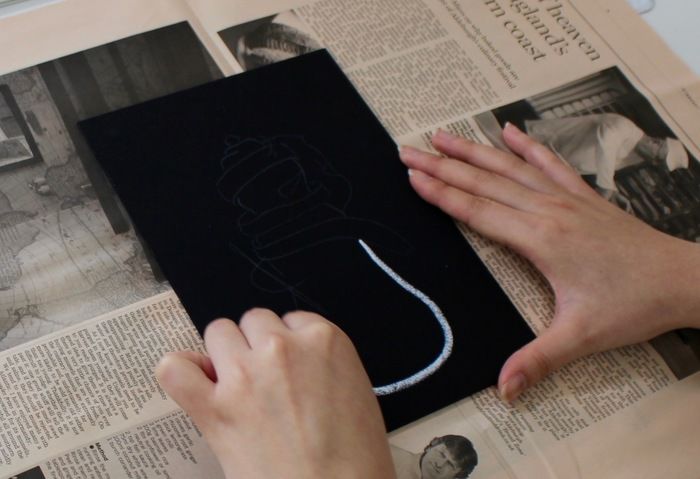 下書きの外枠を白いチョークでなぞっている様子