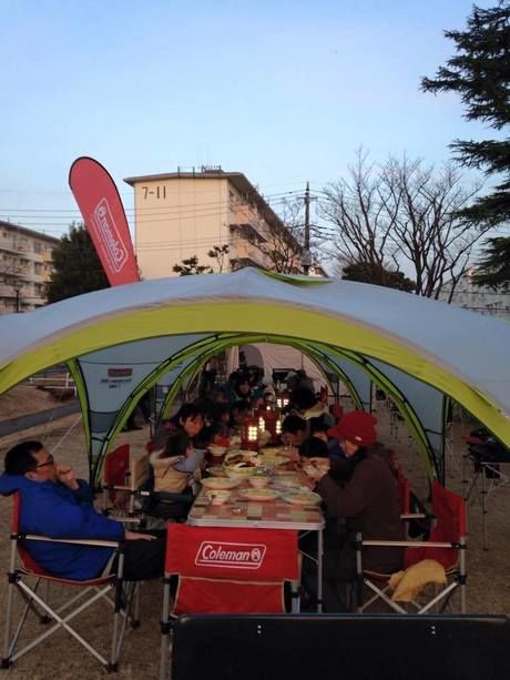 タープの下で夕食を囲む人々