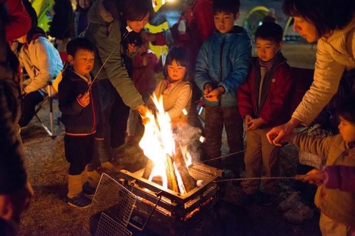 たき火で焼きマシュマロを作る子供