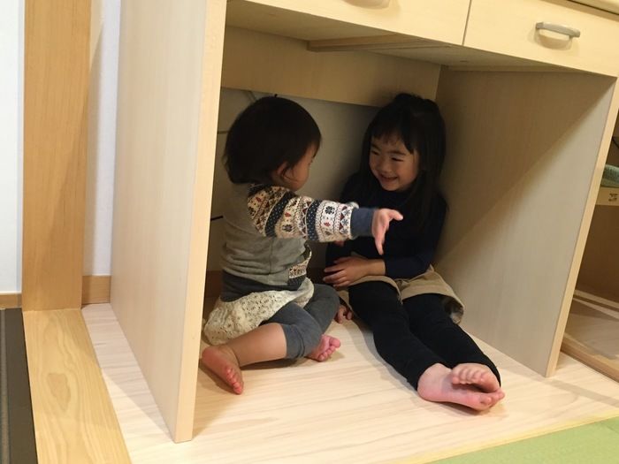 机の下でお話する姉妹