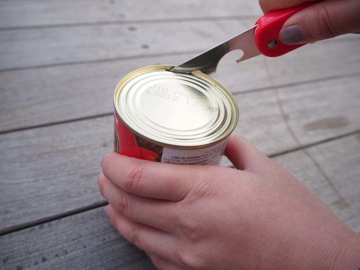 缶詰を缶切りで開けている様子