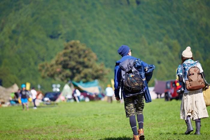 大きなリュックを背負ってキャンプ場を歩く男女