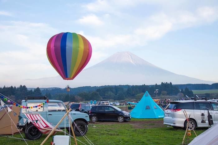 賑やかなキャンプ場とカラフルな気球と富士山