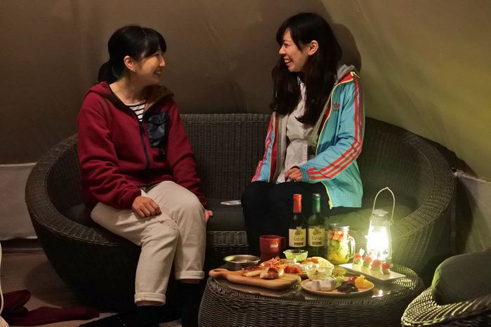テント内の椅子でおしゃべりする女性
