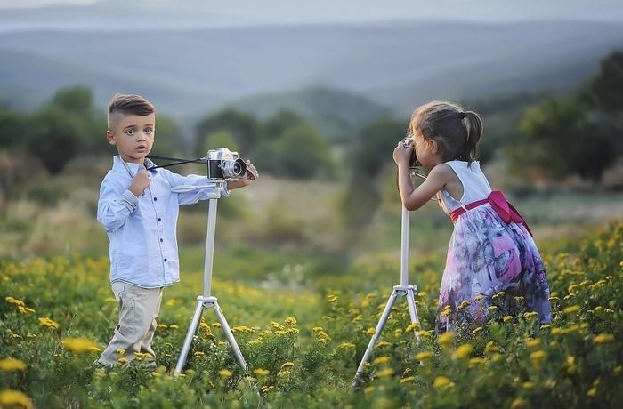 お花畑でカメラで写真を撮る子供たち