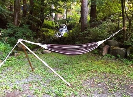 林間の川のほとりにハンモックスタンドを使ってハンモックを設営した様子