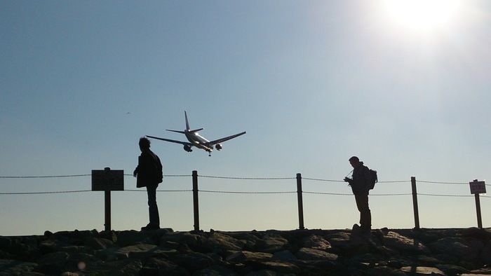 飛行機の後ろ姿を撮る男性の影