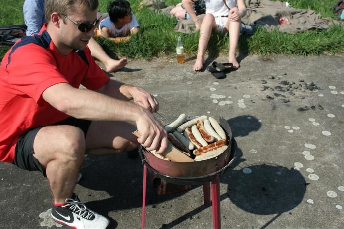バーベキューグリルでソーセージを焼く男性