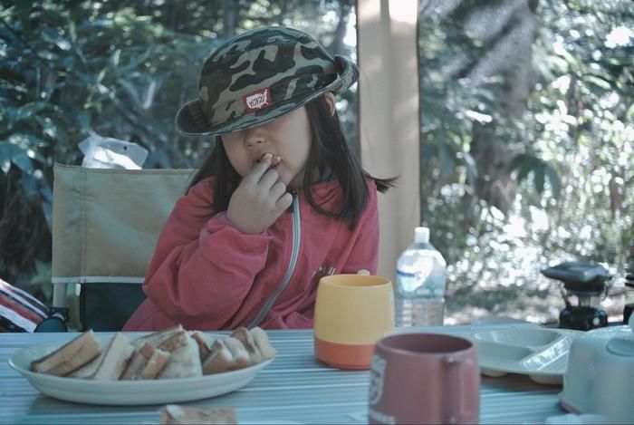 キャンプでサンドイッチを食べる女の子
