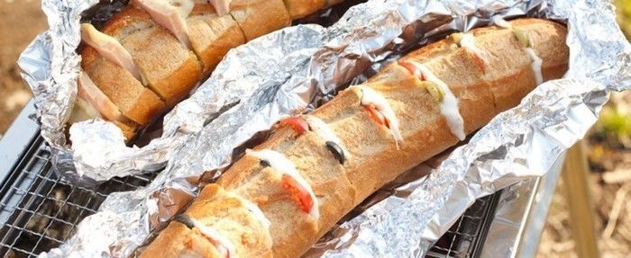 フランスパンをアルミホイルに包んで網で焼いている写真