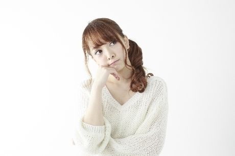 頬杖をついて首をかしげる女性