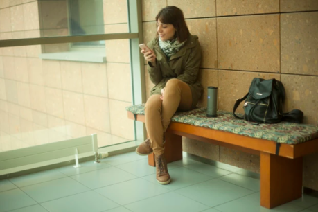 ベンチに座りYecup365で携帯を充電する女性