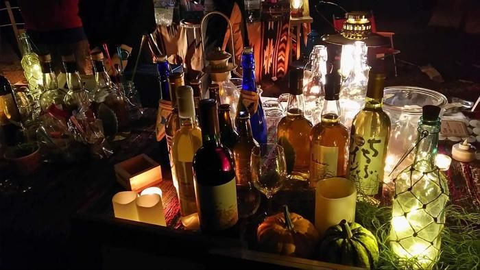 机の上におかれたたくさんのお酒の瓶がライトに照らされている様子