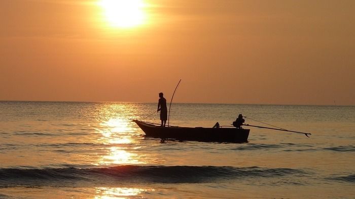 夕陽が沈む海でボートにのる2人