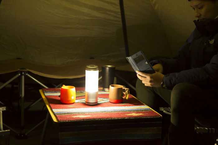 光ったPLAYFUL BASE / LANTERN SPEAKER BOTTLE.をテーブルに置く男性