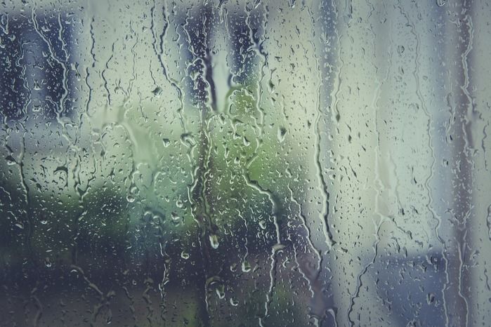 窓にかかった雨の水滴が流れ落ちる様子