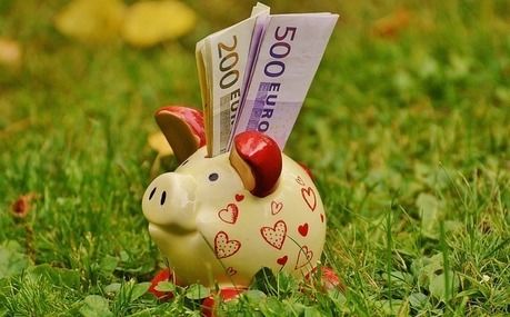 お金が差し込まれたブタの貯金箱