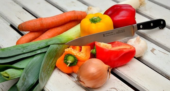 木の上んのせられた様々な野菜と包丁