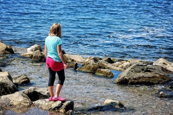 海の岩場に立つ女性