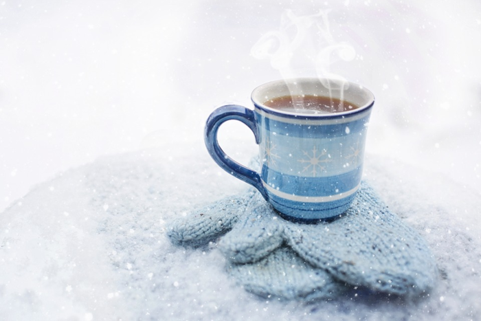雪の中ミトンの上に置かれたホットコーヒー