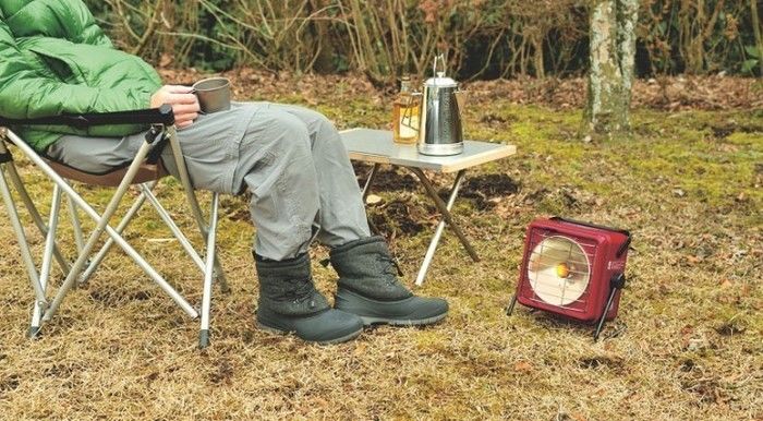 キャンプチェアでくつろぐ男性と電気ヒーター