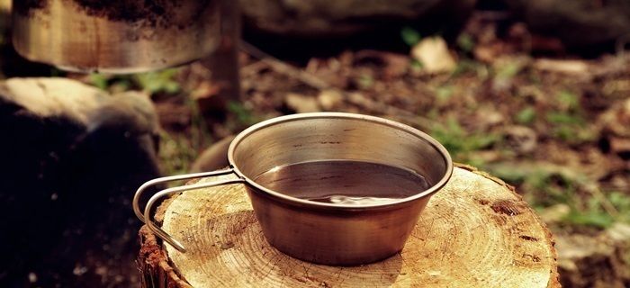 切り株の上に置かれたコーヒーの入ったキャンプマグ