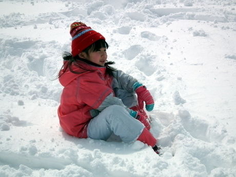 積もった雪に座る子供