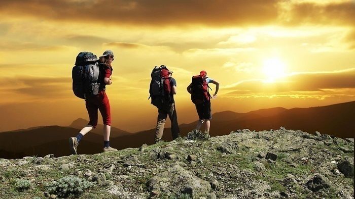 夕日が沈む山に登る男性たち