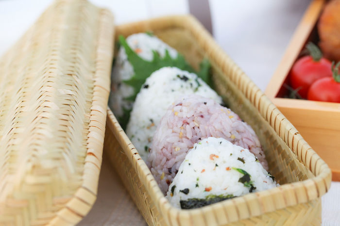 竹カゴのお弁当箱に入った混ぜ込みおにぎり