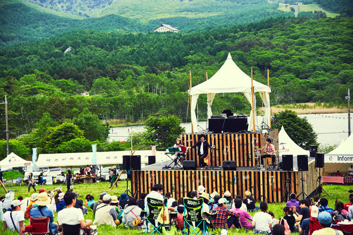 CHUMS CAMPのステージ上で楽器を演奏するアーティストとそれを見る人々