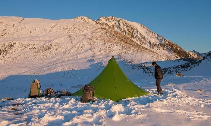 雪山でテントを張ってキャンプをする男性