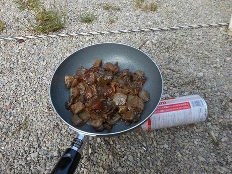 外でフライパンで調理している様子