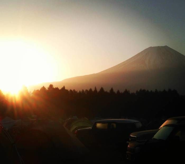 日の出の日差しを浴びる富士山と車