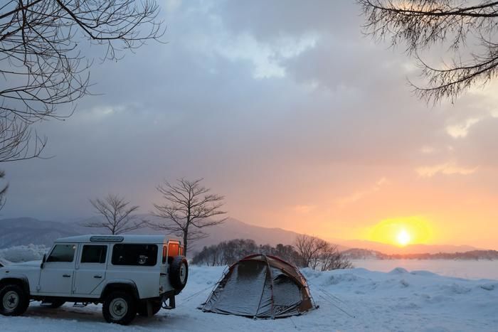 朝日と雪の上に張られたテント