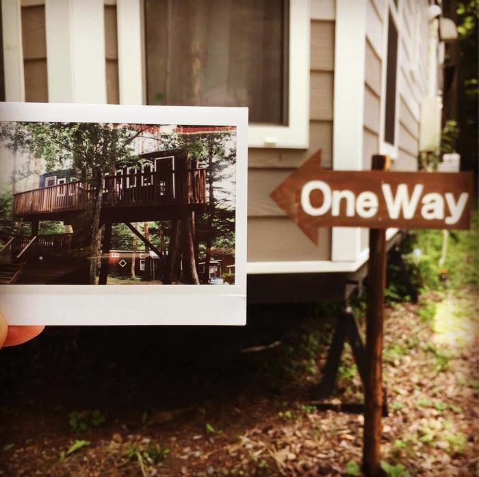 OneWayの看板とその矢印の先に合わせてツリーハウスの写真を持って撮った写真