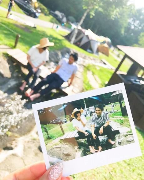 カップルが楽しそうに話す様子を収めた写真を手にもち撮った写真