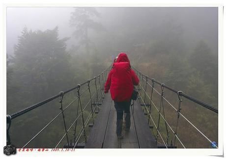 悪天候の中レインウェアを着て橋を渡る人