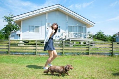休暇村伊良湖オートキャンプ場の白いコテージの前で犬とはしゃいでいる女性