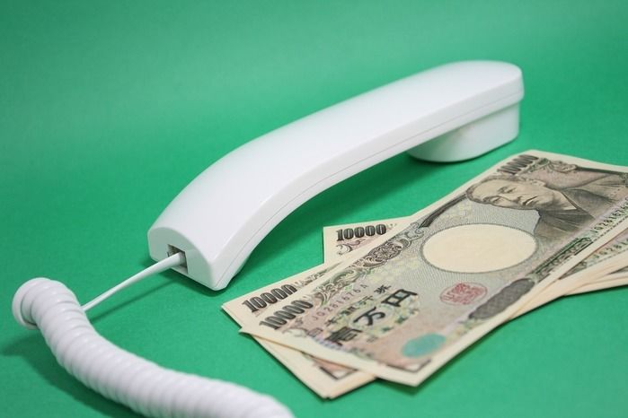 電話の受話器と横に置かれた一万円札