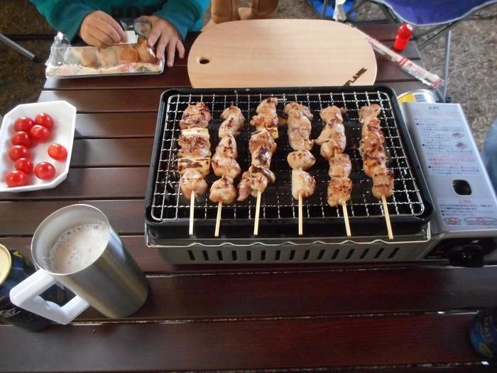 網に串刺しにした鶏肉を置いて焼き鳥を作っている様子